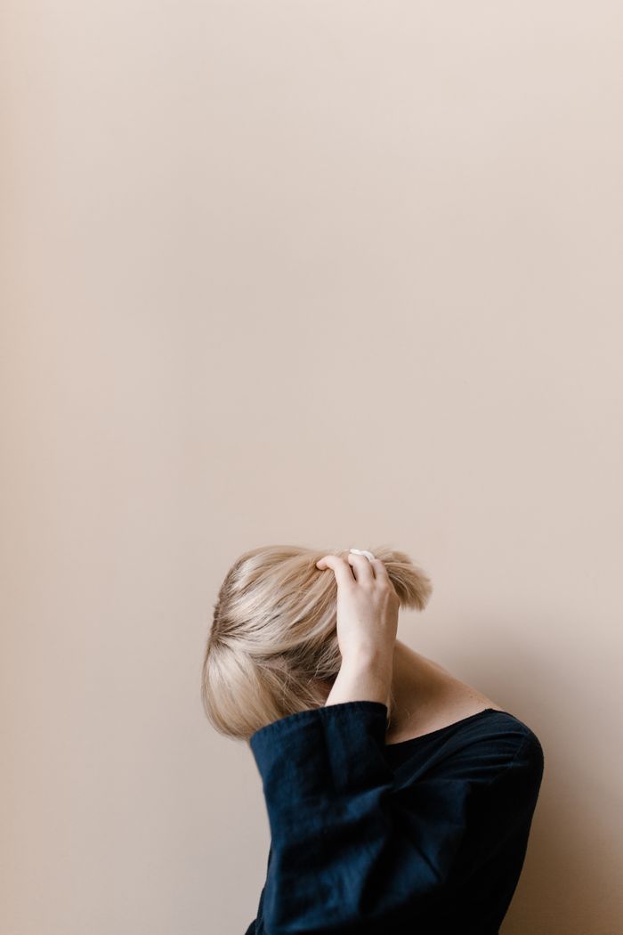 A serene portrait of a young woman with blonde hair, showcasing minimalist fashion and a neutral background.