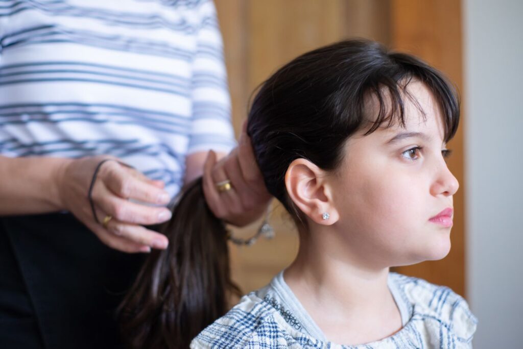 A close-up of a girl having her hair styled, embodying tenderness and care.